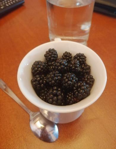 a bowl of blackberries on a table next to a glass at Etno house HAPPY VILLAGE in Cetinje