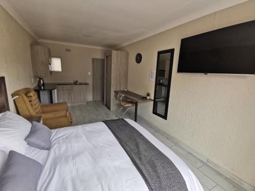 a hotel room with a bed and a flat screen tv at Up21 Guest House in Boksburg