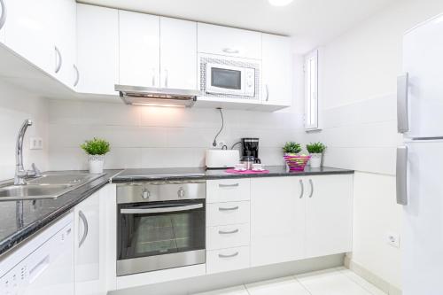- une cuisine blanche avec des placards blancs et un four micro-ondes dans l'établissement Apart-rent Apartamento Francesc Macia 2º 2004, à Roses