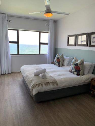 a bedroom with a large bed with a large window at Umdloti Cabanas in Umdloti
