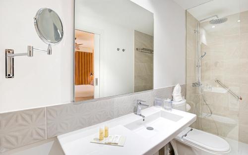 a bathroom with a sink and a toilet and a mirror at Hotel Arena Castillo - New Opening sum 25! in Caleta De Fuste