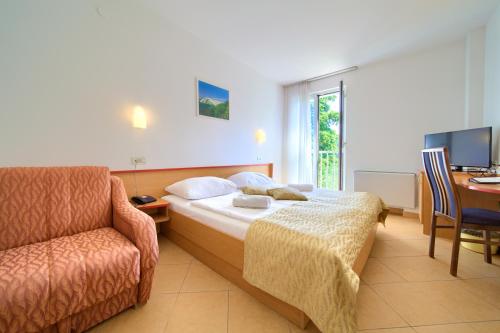 a hotel room with a bed and a chair and a desk at Villa Lovorka - Hotel Resort Dražica in Krk
