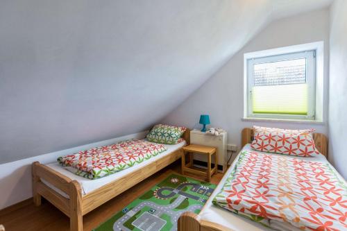 a attic room with two beds and a window at Ferienhaus Kikki in Friedrichskoog-Spitz