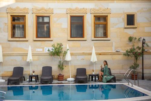a woman sitting next to a swimming pool at Göreme Reva Hotel in Goreme