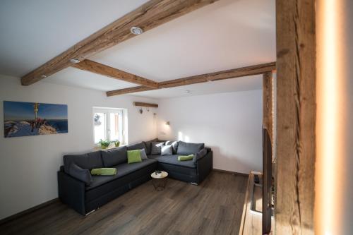 a living room with a black couch and wooden beams at Ferienwohnung Zwölferkante in Grainau