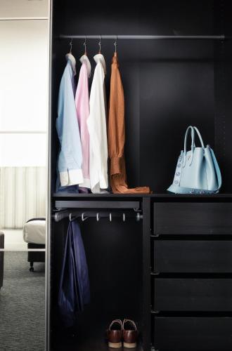a black closet with a rack of clothes and shoes at Comfort Hotel East Melbourne in Melbourne