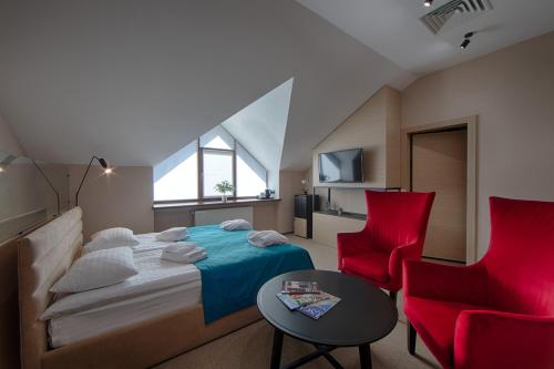 a bedroom with a bed and two red chairs at Hotel Riders Equides club in Lesniki