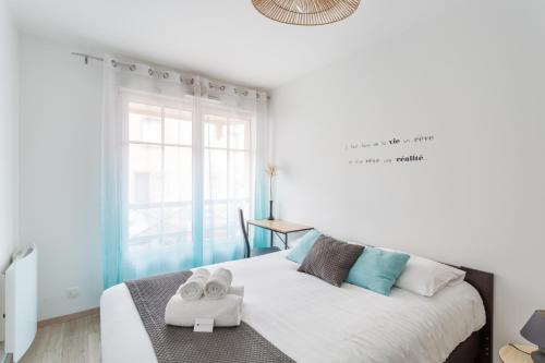 Un dormitorio blanco con una cama con toallas. en L'Echo des Vagues, en Saint-Malo