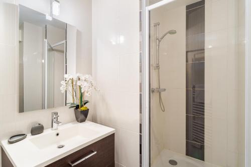 ein weißes Bad mit einem Waschbecken und einer Dusche in der Unterkunft L'Echo des Vagues in Saint-Malo
