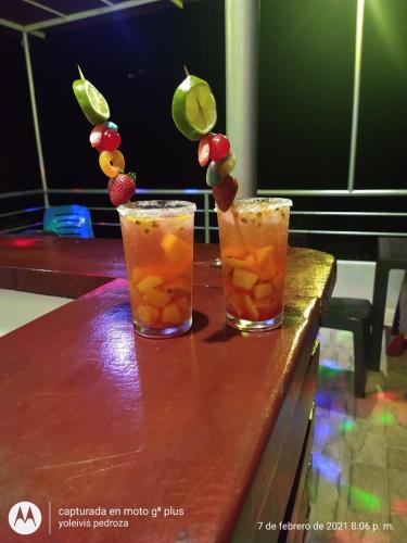 two cocktails with fruit on top of a wooden table at Hostal Alto de la Montaña in Minca