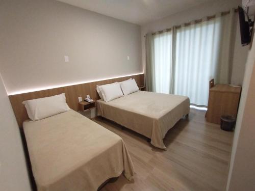 ein Hotelzimmer mit 2 Betten und einem Fenster in der Unterkunft Rambo Hotel in Alegrete