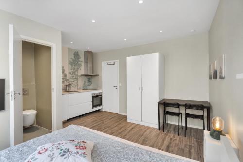 a bedroom with a bed and a table and a kitchen at Central Studio Apartment Apt 103 in Stavanger