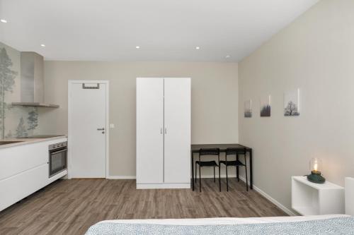 a white kitchen with a desk and a table at Central Studio Apartment Apt 103 in Stavanger