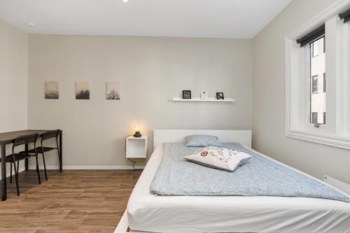 a white bedroom with a bed and a table at Central Studio Apartment Apt 103 in Stavanger