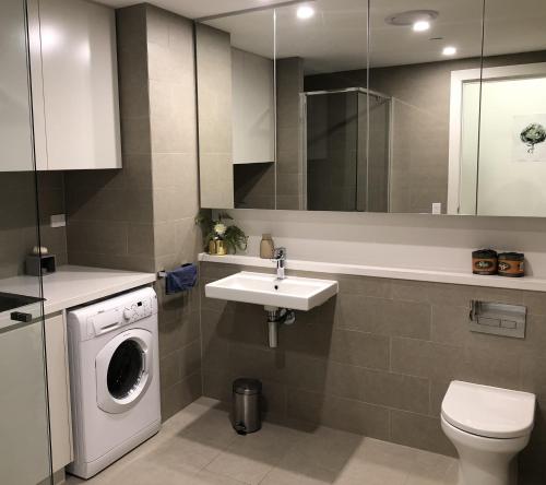 a bathroom with a washing machine and a sink at Parkview Modern Apartment w Parking @ Olympic Park in Sydney