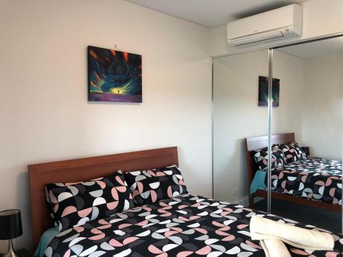 1 dormitorio con cama y espejo en Parkview Modern Apartment w Parking @ Olympic Park en Sídney