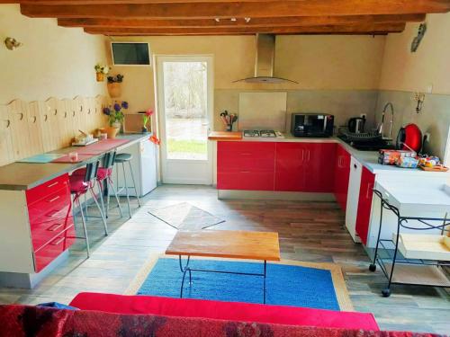 una cocina con armarios rojos y azules y una mesa. en La Maison entièrement équipée - Boulangerie, en Saint-Pierre-les-Étieux