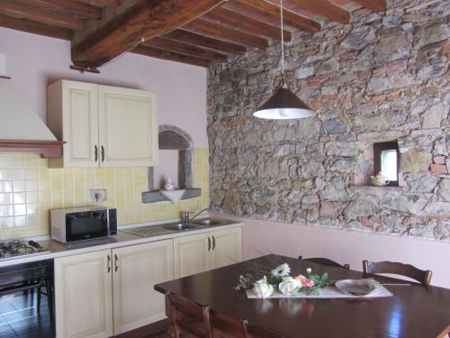 a kitchen with a table and a stone wall at Tenuta Seripa in Sassetta