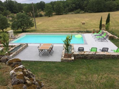 a pool with chairs and a table and a frisbee at Gites de Combarel in Corn