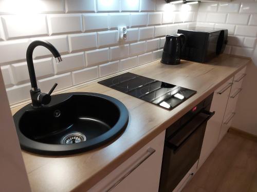 a kitchen counter with a sink and a stove at Polanki Park Apartament LEON in Kołobrzeg