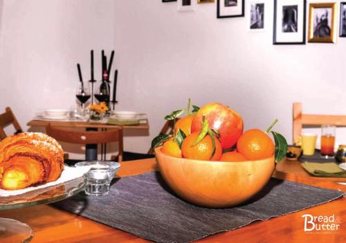 a wooden bowl of fruit on a table with a bowl of bread at Bread & Butter in Albignasego