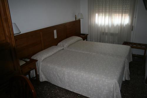 een slaapkamer met een bed met een wit dekbed bij Hostal Puente de Piedra in Zaragoza