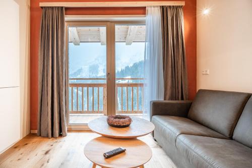 a living room with a couch and a large window at Naturhaus am Arlberg in Warth am Arlberg