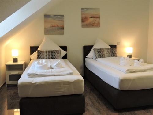 2 Betten in einem kleinen Zimmer mit 2 Lampen in der Unterkunft Ferienwohnungen Haus Scheidter 40 in Saarbrücken