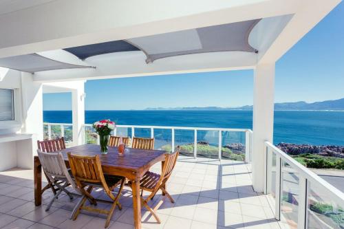 a dining room with a table and chairs and the ocean at 49 on Cliff in Gansbaai