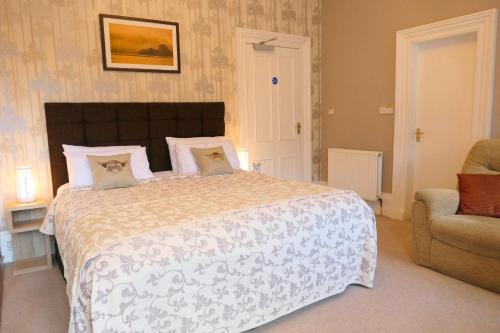 a bedroom with a large bed and a chair at The Gordon Guest House in Ballater