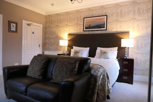 a bedroom with a bed and a leather couch at The Gordon Guest House in Ballater