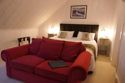um quarto com uma cama e um sofá vermelho em The Gordon Guest House em Ballater