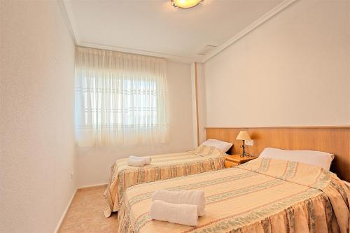 1 dormitorio con 2 camas y ventana en 020 - Senya Gran Playa 001 - comfortHOLIDAYS, en Santa Pola