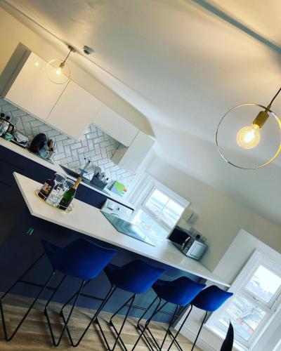 a kitchen with a counter and blue stools at Seabourne Penthouse Stunning Seaviews with optional hot tub hire at Homesweetholidayhomes in Scarborough