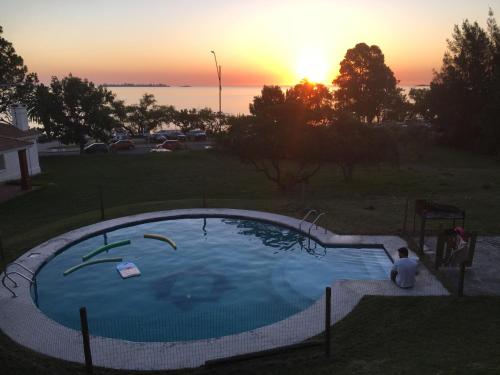 une personne assise devant une piscine au coucher du soleil dans l'établissement Apartamento con excelente ubicación y vista al Rio, à Colonia del Sacramento