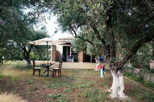 a table and chairs under an umbrella in a yard at Private Villa Dula with Ocean View in Corfu Town