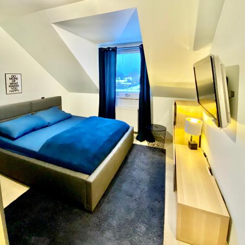 a bedroom with a blue bed and a window at Lake View Ostróda Luxury Apartment in Ostróda