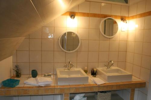 a bathroom with two sinks and two mirrors at Au Relais de Chaussy in Chaussy