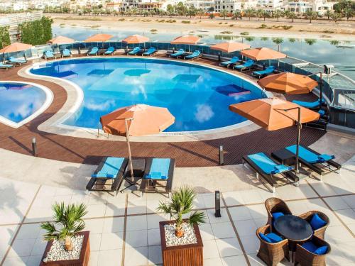 an overhead view of a pool with chairs and umbrellas at Novotel Abu Dhabi Gate in Abu Dhabi