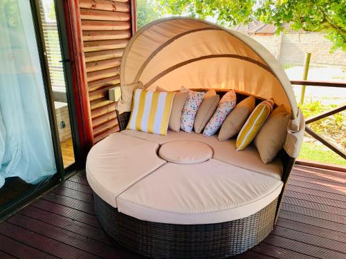 a wicker chair with pillows on a porch at Cabins Sodwana Bay - antibootika in Sodwana Bay