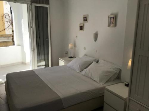a white bedroom with a bed and a window at Mimis & Connie 1 in Karpathos Town