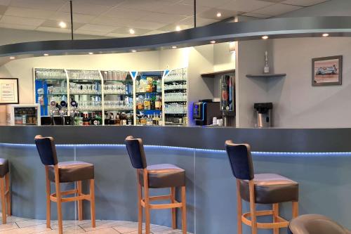 a bar with four chairs in front of a counter at Hotel Le Circuit Le Mans in Le Mans