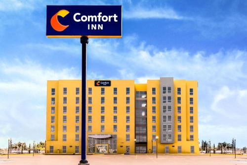 a hotel sign in front of a yellow building at Comfort Inn Delicias in Delicias