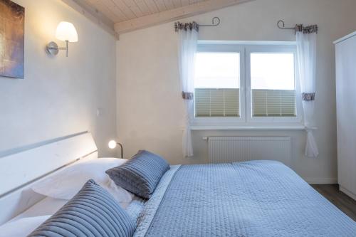 a bedroom with a bed with blue pillows and a window at Ferienhaus Strandkrabbe in Dagebüll