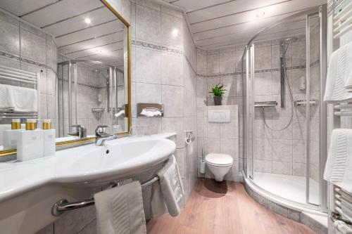 a bathroom with a sink and a tub and a toilet at Boutique Hotel ANYBODY in Saalbach Hinterglemm