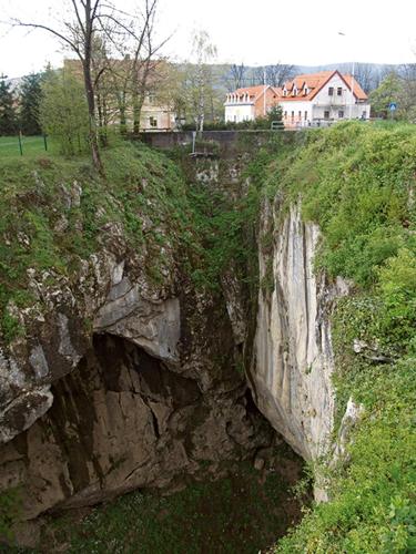 a rock cliff with a house on top of it at Apartmani Lovro in Ogulin