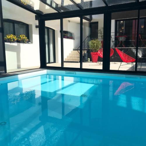 a swimming pool with blue water in a house at Le Cornouaille Hotel & Spa in Bénodet
