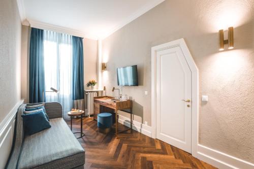 Camera con divano, scrivania e finestra. di Hotel Reine Victoria by Laudinella a Sankt Moritz