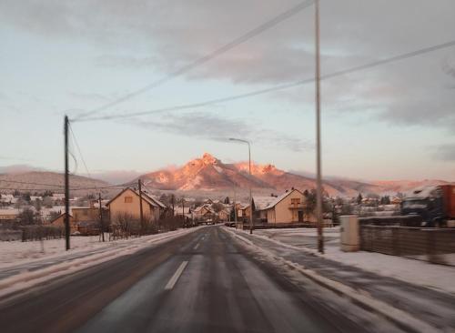 a snow covered road with a mountain in the background at Apartmani Lovro in Ogulin