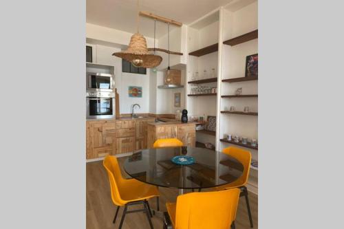 une cuisine avec une table en verre et des chaises jaunes dans l'établissement Venice Beach LA BAULE appartement face à la mer!, à La Baule
